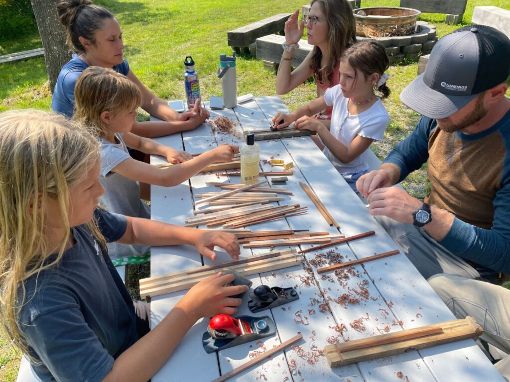 family at picnic table learning to make chopsticks