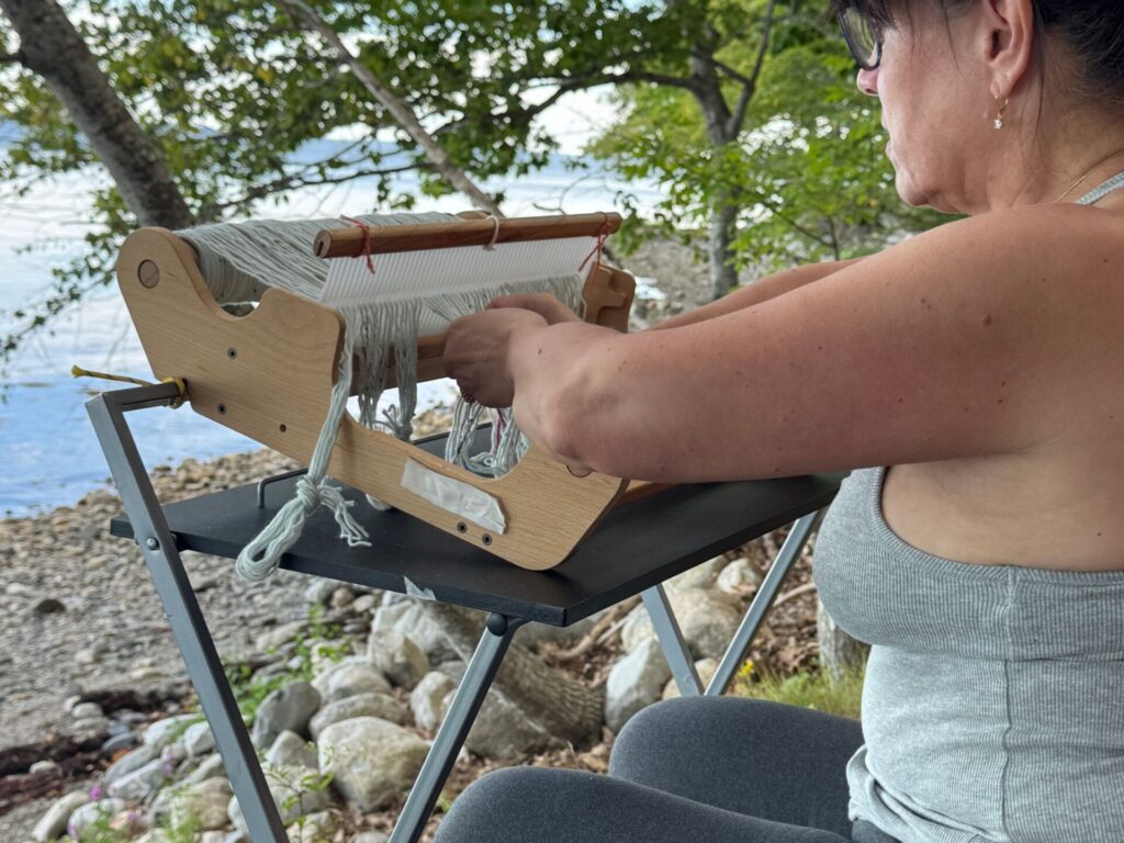 woman weaving at her oceanfront tent site