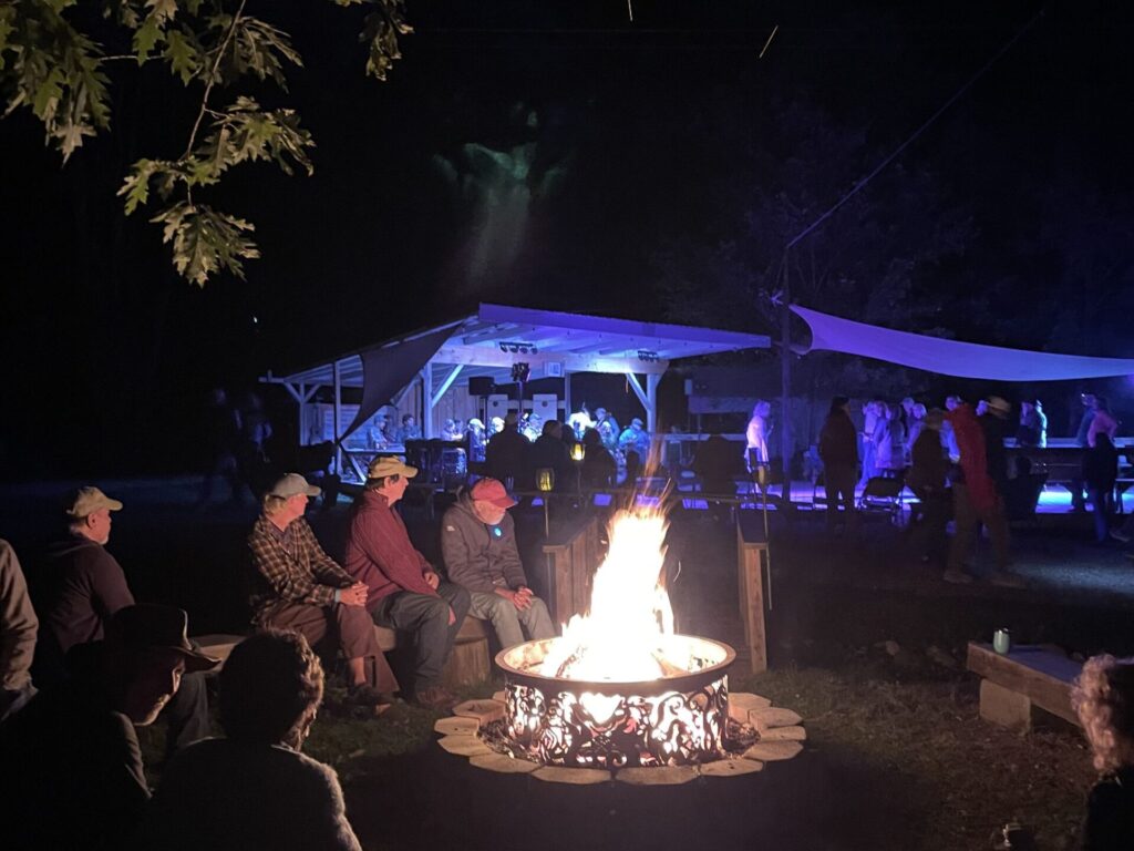 group at campfire with dancing in the background